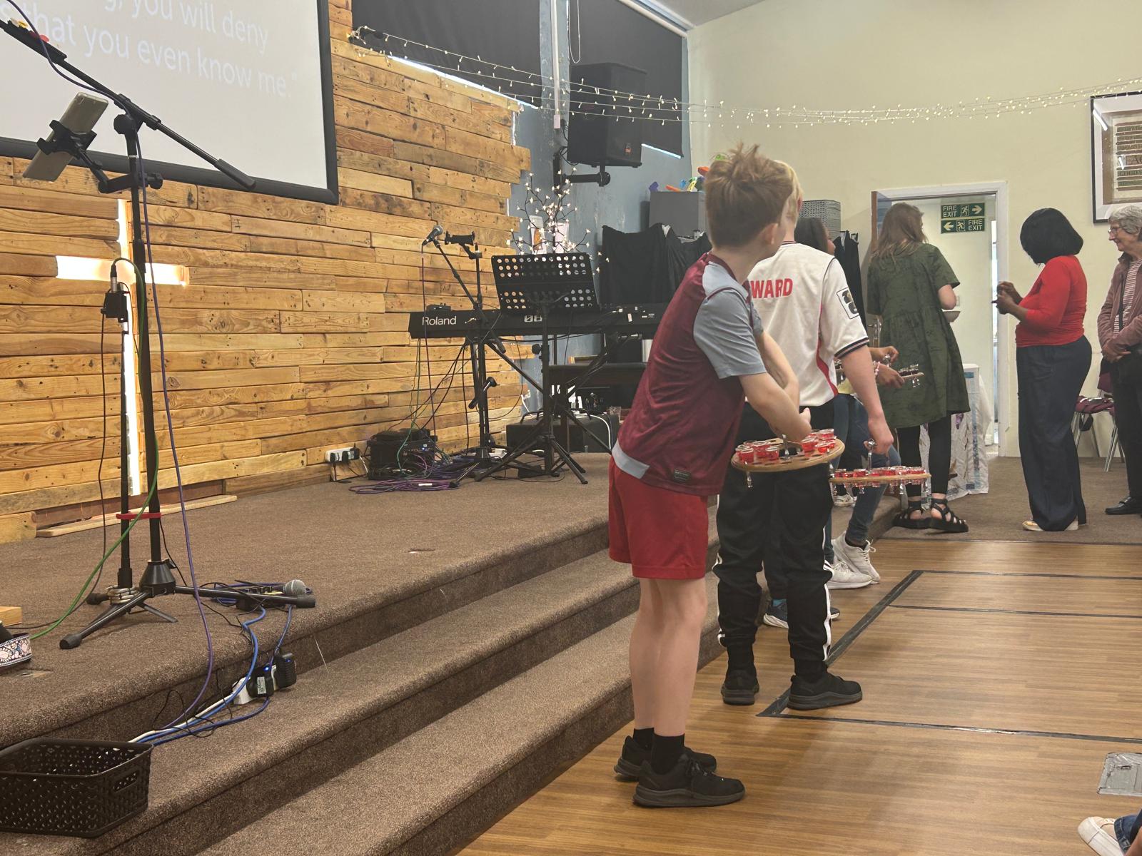Young people carrying trays of communion cups to the congregation during a family service