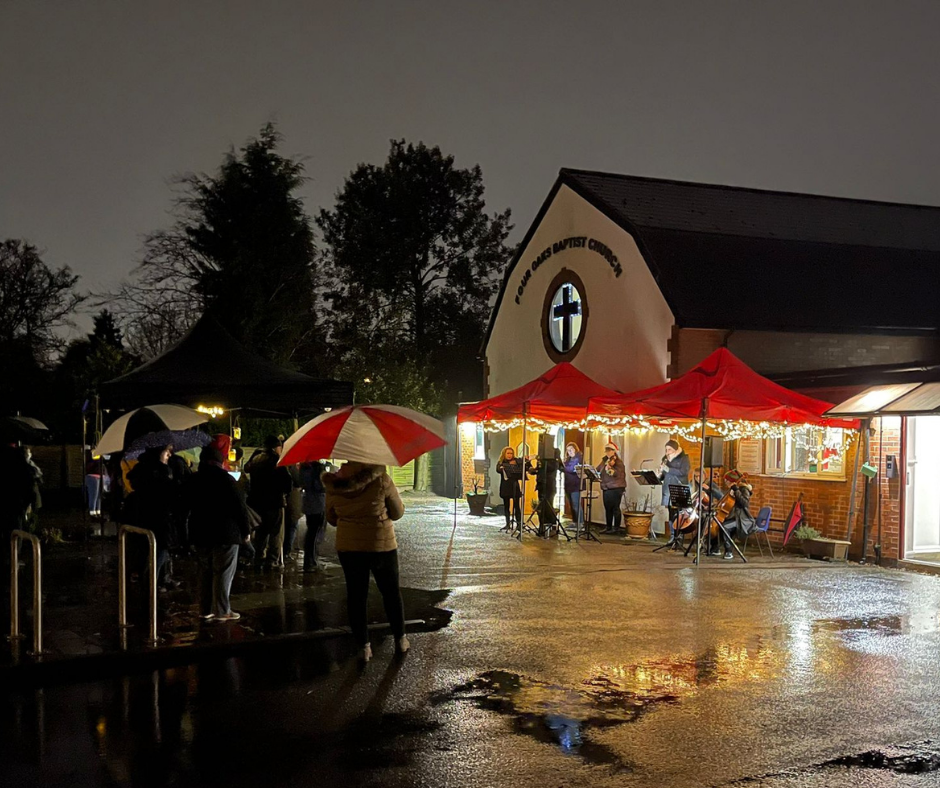 Musicians playing under red gazebos outside the church on a rainy evening