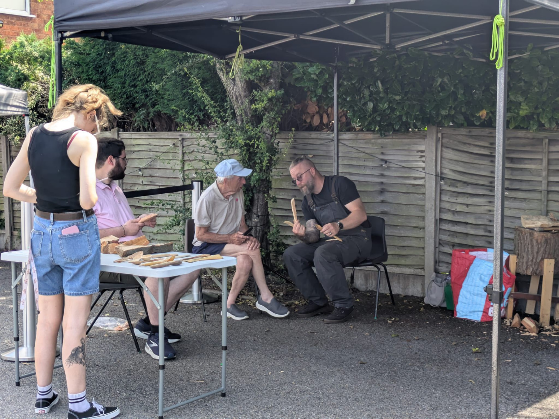 People learning wood carving under a gazebo outside the church