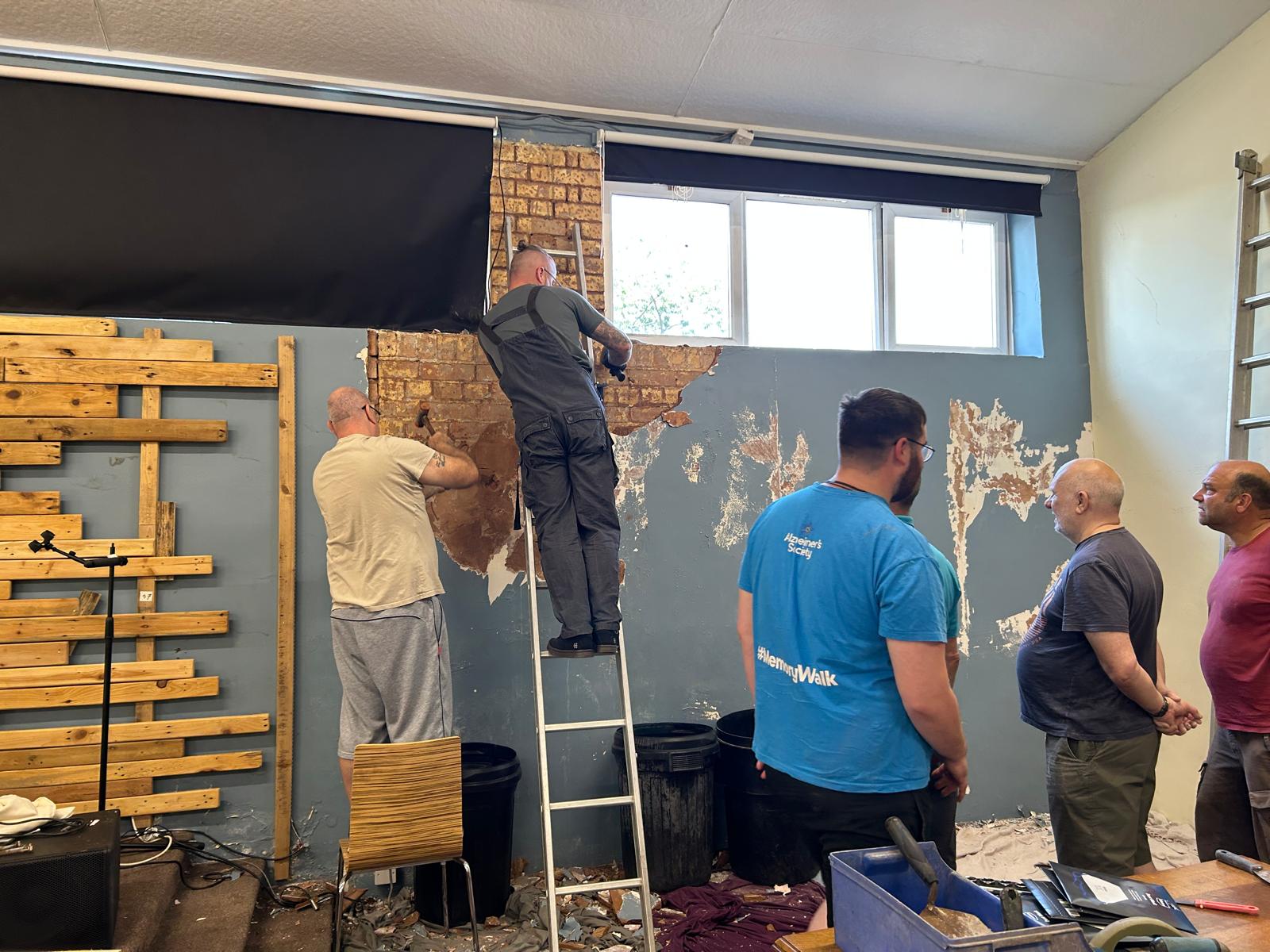 Volunteers stripping plaster back to exposed brick inside the church