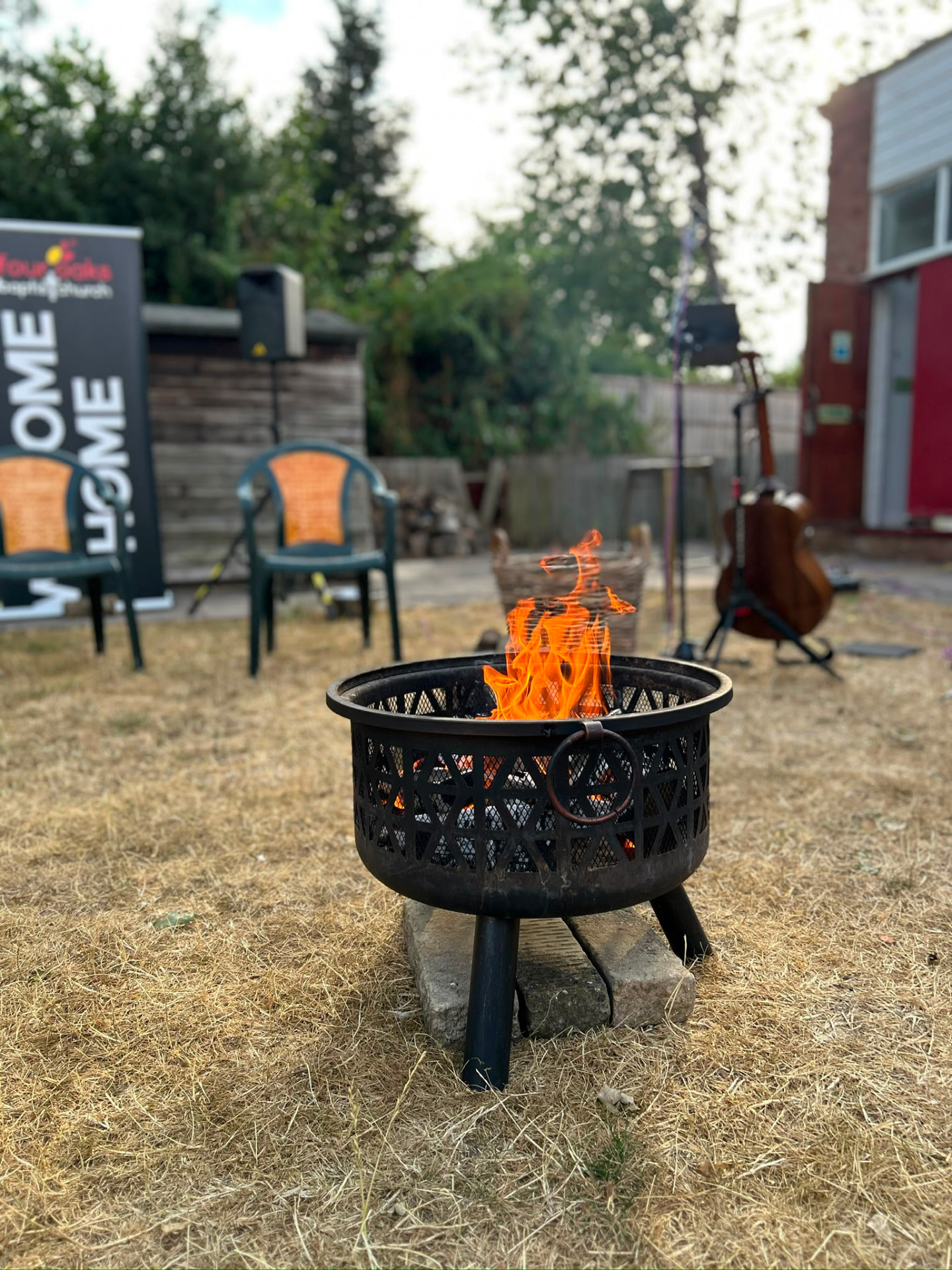 A fire pit burning in the church garden with guitars nearby