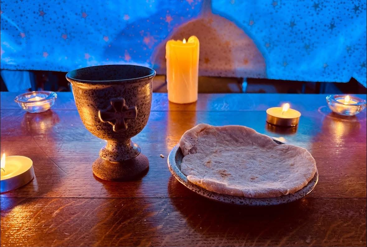 Communion cup, bread and candles on a wooden table