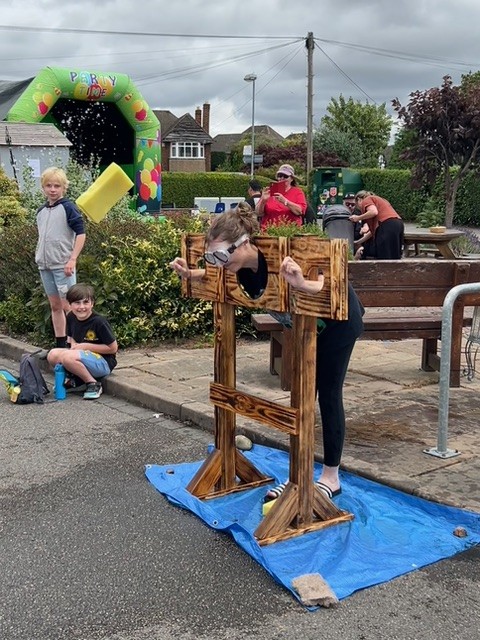 Children watching someone in wooden stocks at the summer fete