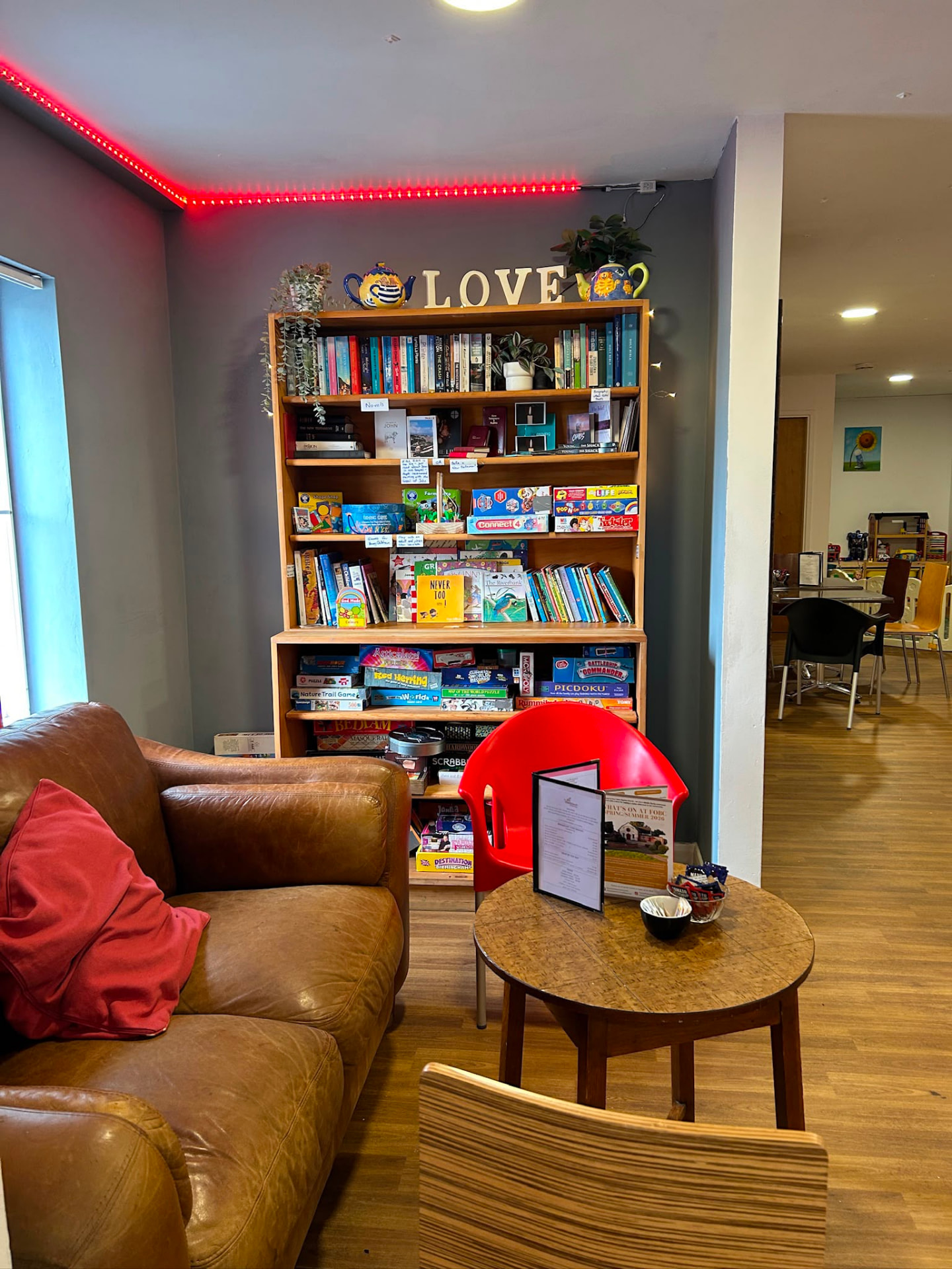 Leather sofa, bookshelves and red neon lighting inside the coffee shop