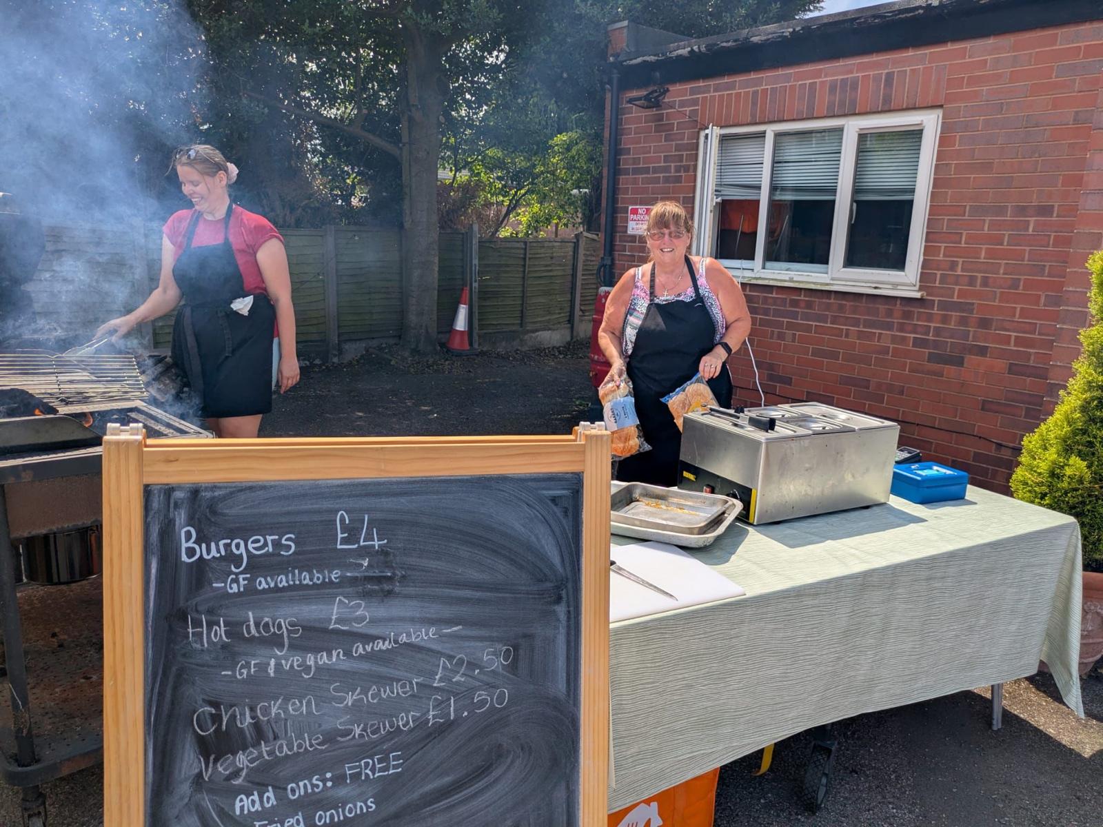 Volunteers cooking burgers and hot dogs on a barbecue outside the church