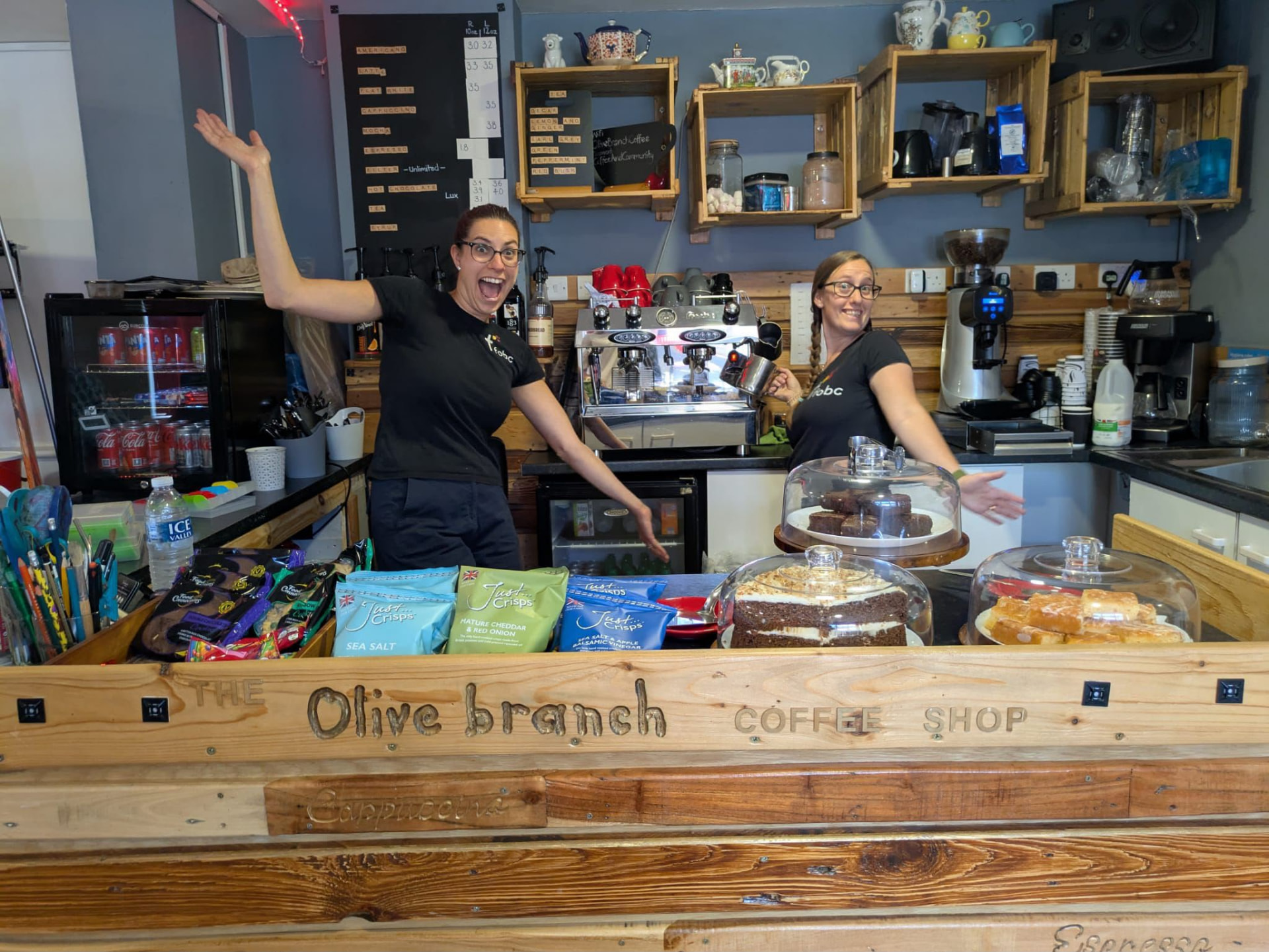 Two volunteers behind the Olive Branch coffee shop counter