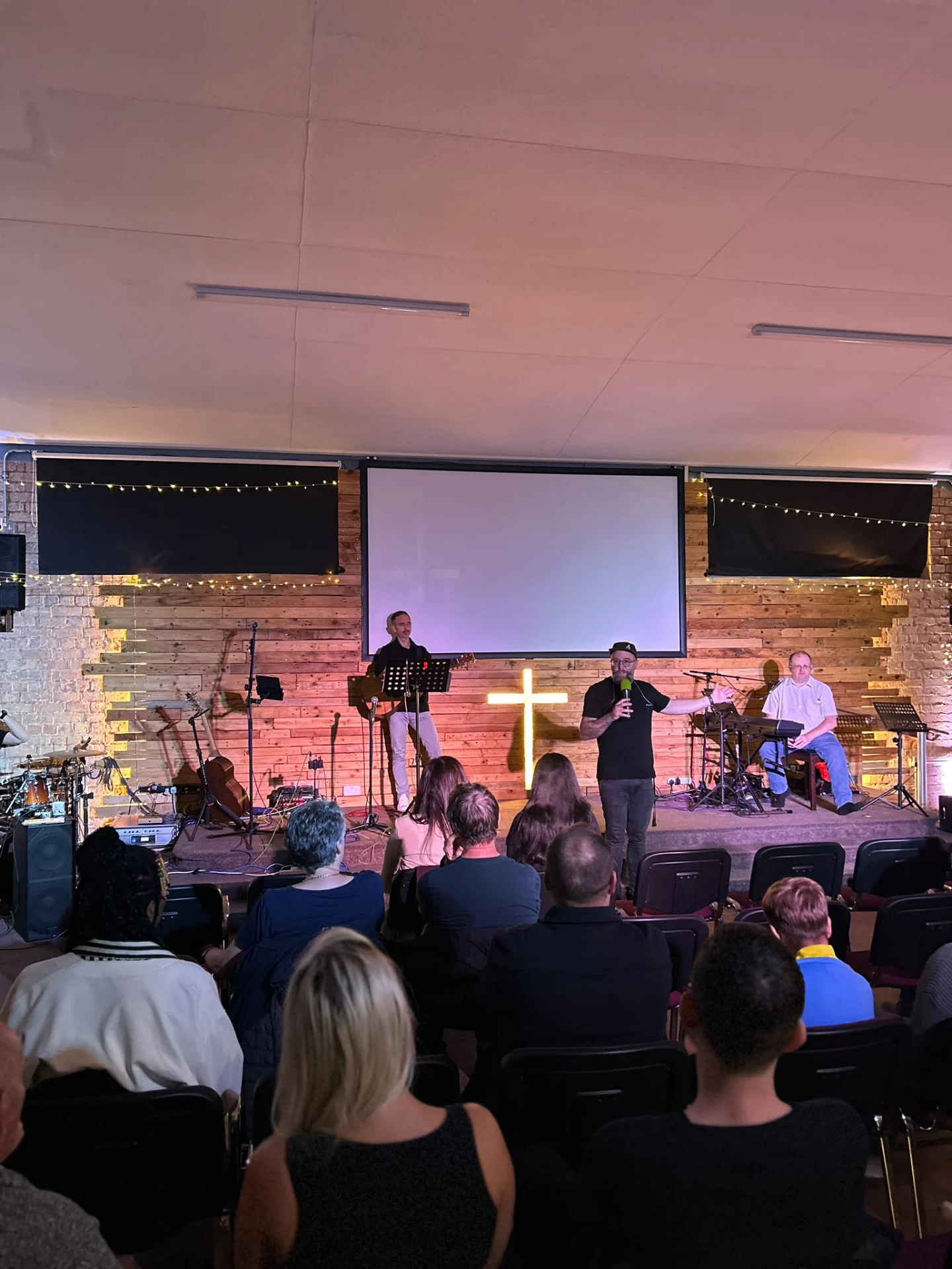 Speaker and worship band on stage at an evening church event