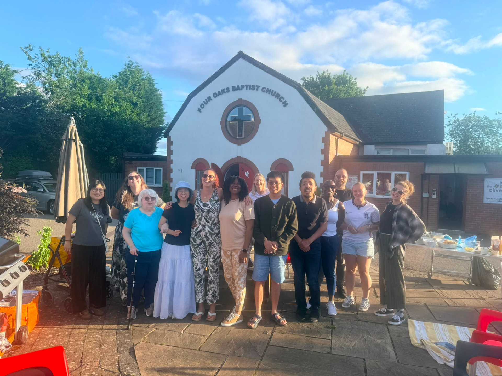 Church family gathered outside Four Oaks Baptist Church on a summer evening
